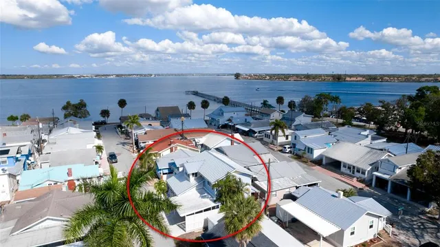 an aerial view of a house with lots of residential buildings ocean and mountain view in back