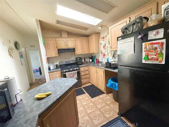 a kitchen with stainless steel appliances granite countertop a refrigerator a sink dishwasher and white countertops with wooden floor