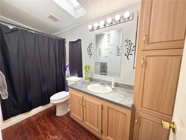 a spacious bathroom with a granite countertop sink toilet a mirror a vanity and shower