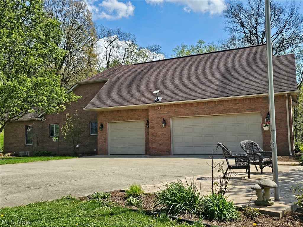 2363 Tabor Ridge Road Northeast New Philadelphia, OH 44663 - Photo 6 of 42 Brick exterior with a multi-car garage, concrete driveway, and mature landscaping