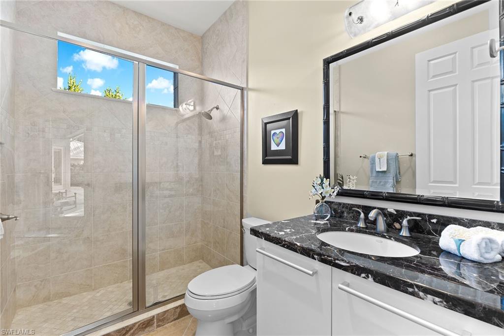 540 Ketch Drive Naples, FL 34103 - Photo 9 of 32 a bathroom with a granite countertop sink a toilet a mirror and shower