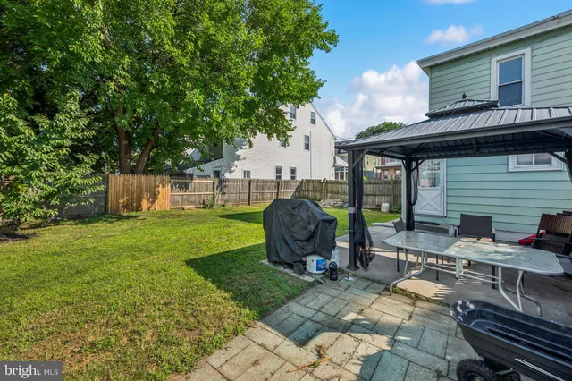 a view of a backyard with table and chairs potted plants and a large tree