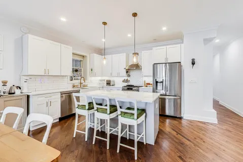 a kitchen with stainless steel appliances a dining table chairs stove refrigerator and cabinets