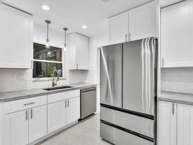 a kitchen with stainless steel appliances white cabinets white stove and a refrigerator with wooden floor