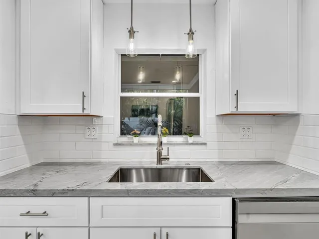 a kitchen with granite countertop white cabinets and stainless steel appliances
