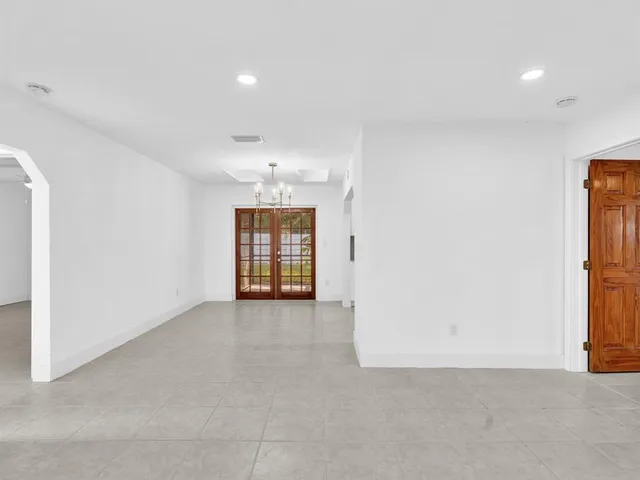 an empty room with chandelier fan and windows