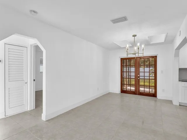 an empty room with windows and chandelier fan