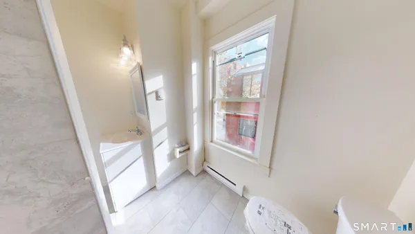 an entryway with wooden floor and a bathroom