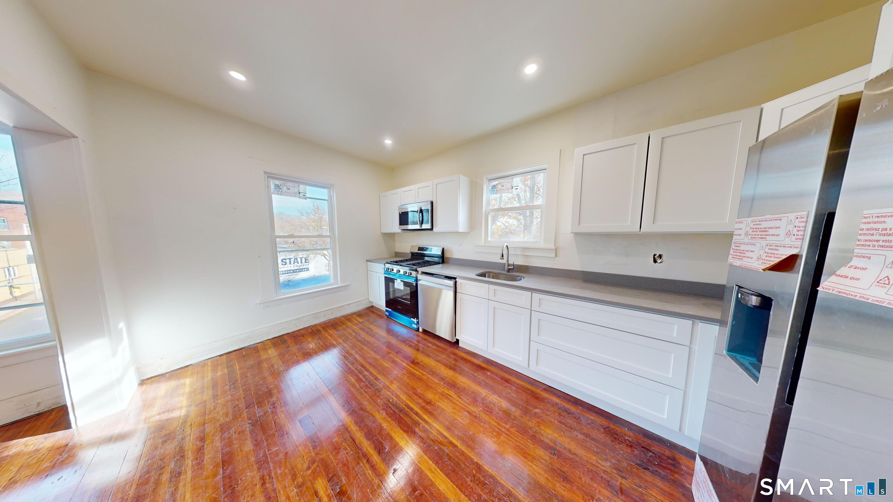 736 Main Street Windham, CT 06226 - Photo 10 of 12 a kitchen with granite countertop wooden floors a sink and appliances