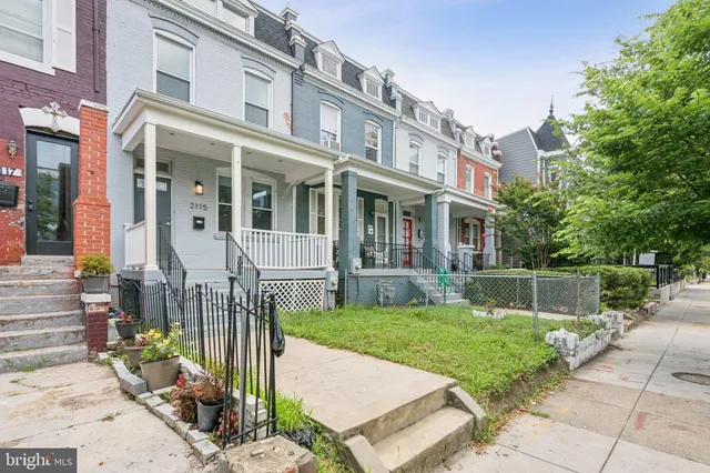 a view of a brick house with a yard and plants