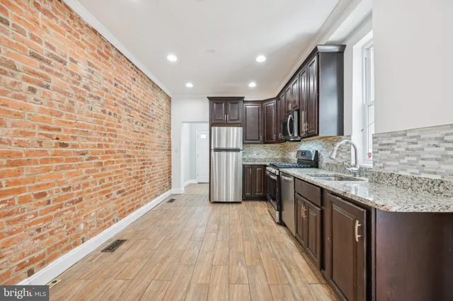 a kitchen with stainless steel appliances granite countertop a refrigerator a sink dishwasher a stove and white countertops with wooden floor