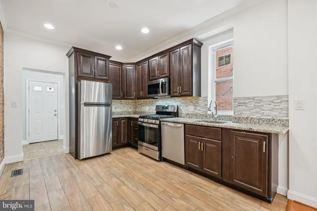a kitchen with stainless steel appliances granite countertop a refrigerator and a stove top oven