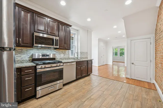 a large kitchen with wooden floors and stainless steel appliances