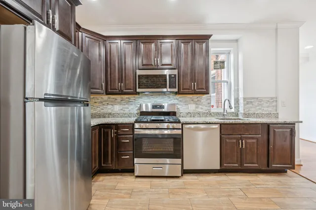 a kitchen with granite countertop a refrigerator and a stove top oven
