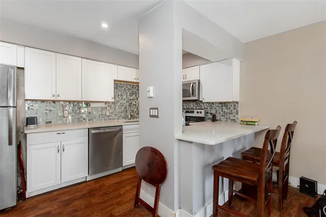 a kitchen with stainless steel appliances a dining table chairs and a refrigerator