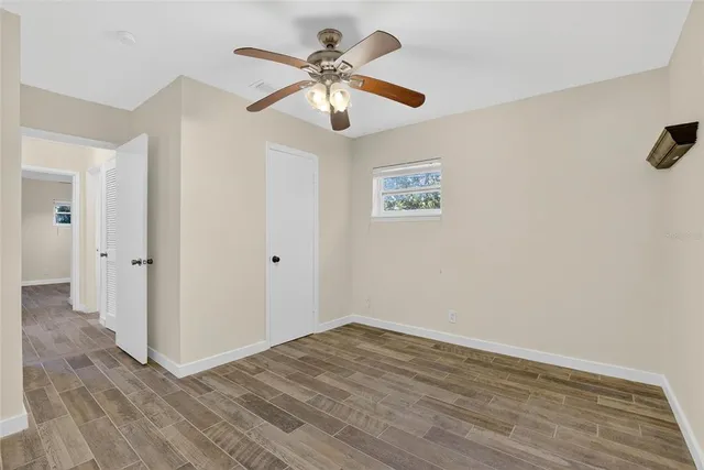 an empty room with a ceiling fan and wooden floor