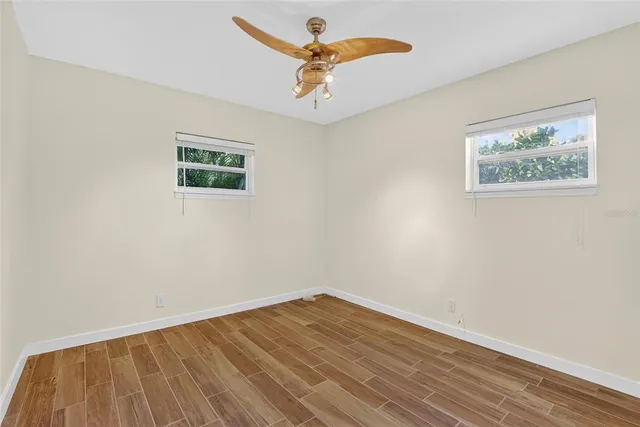 an empty room with wooden floor chandelier fan and closet area