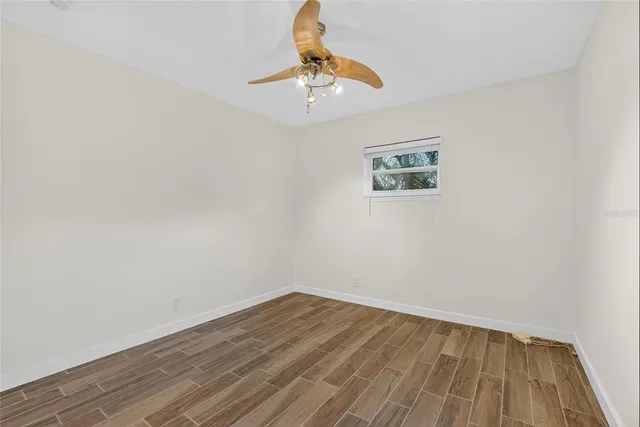 a view of an empty room with wooden floor and windows