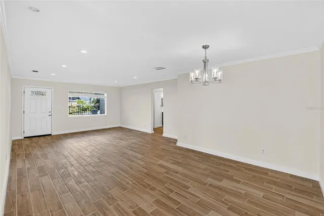an empty room with wooden floor and a kitchen