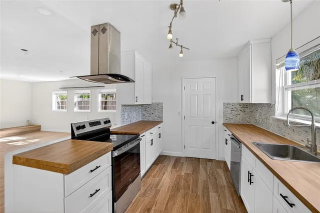 a kitchen with stainless steel appliances granite countertop a sink dishwasher a refrigerator and a stove with wooden floor