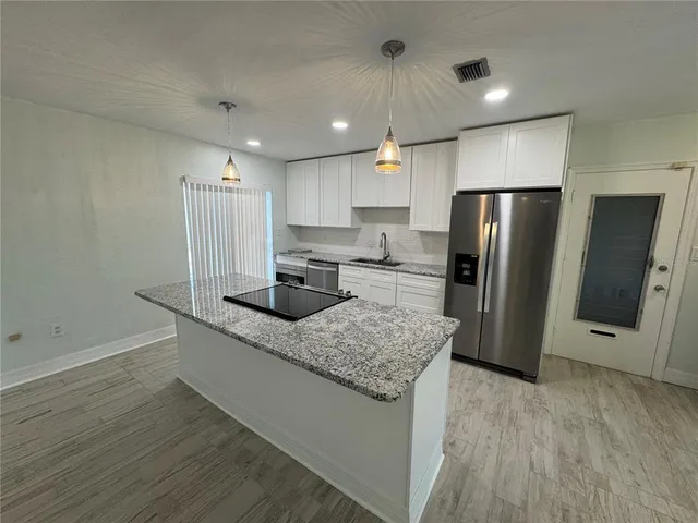 a kitchen with stainless steel appliances granite countertop a refrigerator a sink and a stove