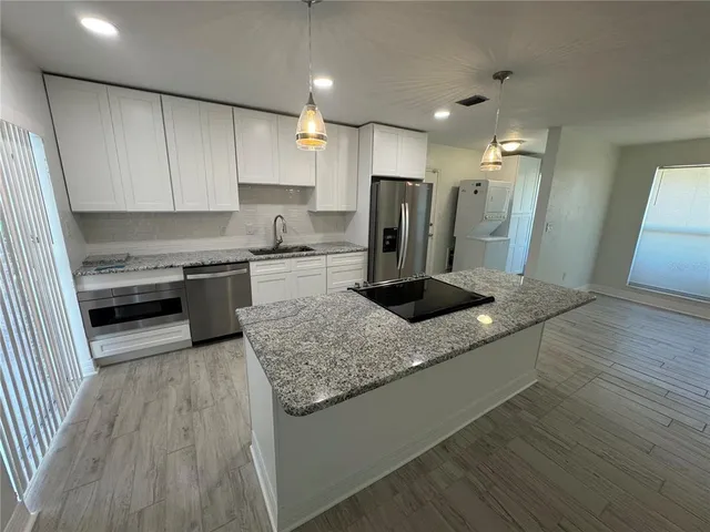 a kitchen with stainless steel appliances granite countertop a sink stove and refrigerator