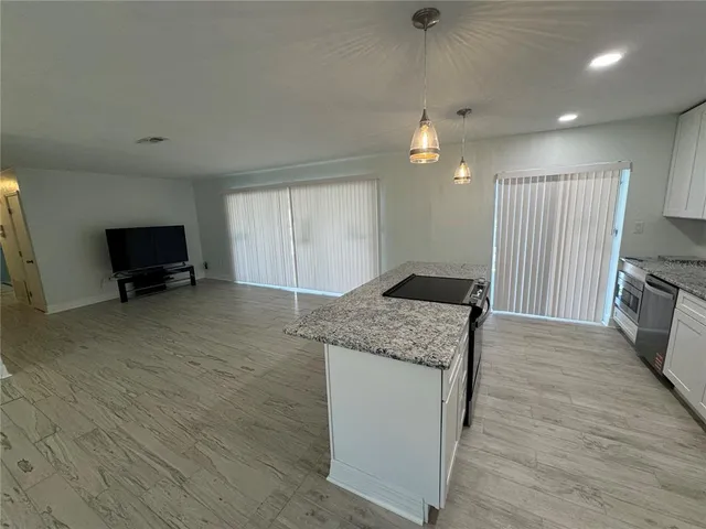 a kitchen with granite countertop a stove and a wooden floor