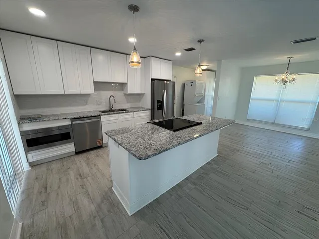 a large kitchen with stainless steel appliances granite countertop a stove a sink and a refrigerator