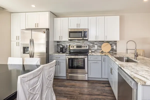 a kitchen with stainless steel appliances granite countertop a stove top oven a sink and white cabinets