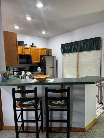 a kitchen with stainless steel appliances granite countertop a table chairs sink and cabinets