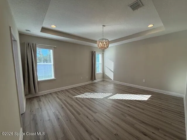 an empty room with wooden floor and chandelier