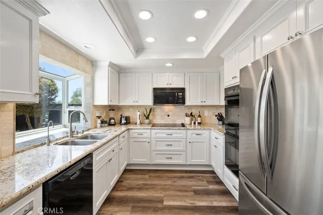 a large kitchen with stainless steel appliances granite countertop a sink stove refrigerator and cabinets