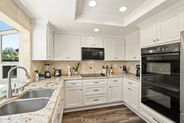 a kitchen with granite countertop a sink stainless steel appliances and cabinets