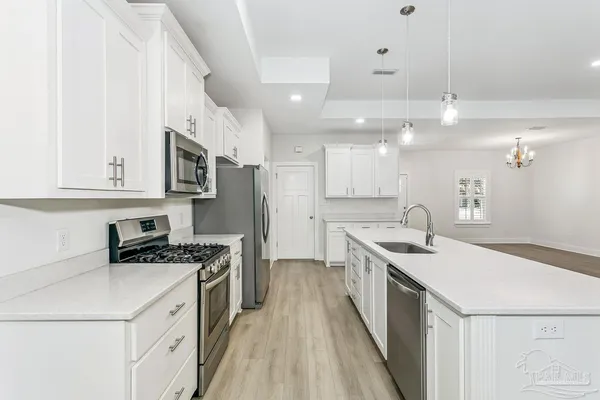 a kitchen with stainless steel appliances a sink a stove a refrigerator and cabinets
