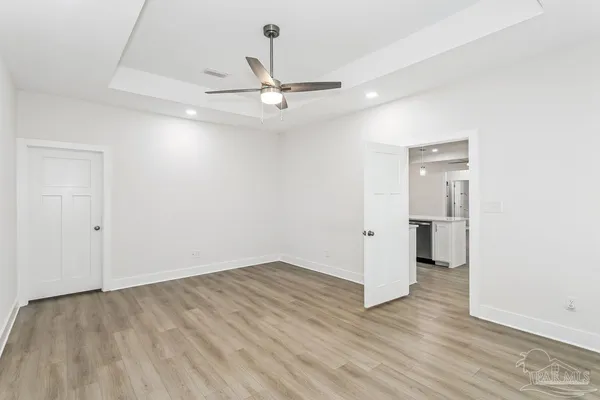 an empty room with wooden floor and ceiling fan