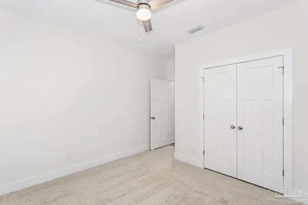 an empty room with a fan & a window