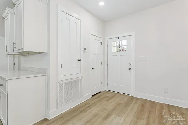 a view of an empty room with wooden floor and closet