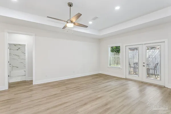 an empty room with wooden floor cabinet and windows