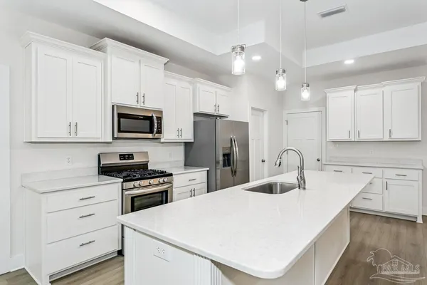 a kitchen with white cabinets stainless steel appliances and sink