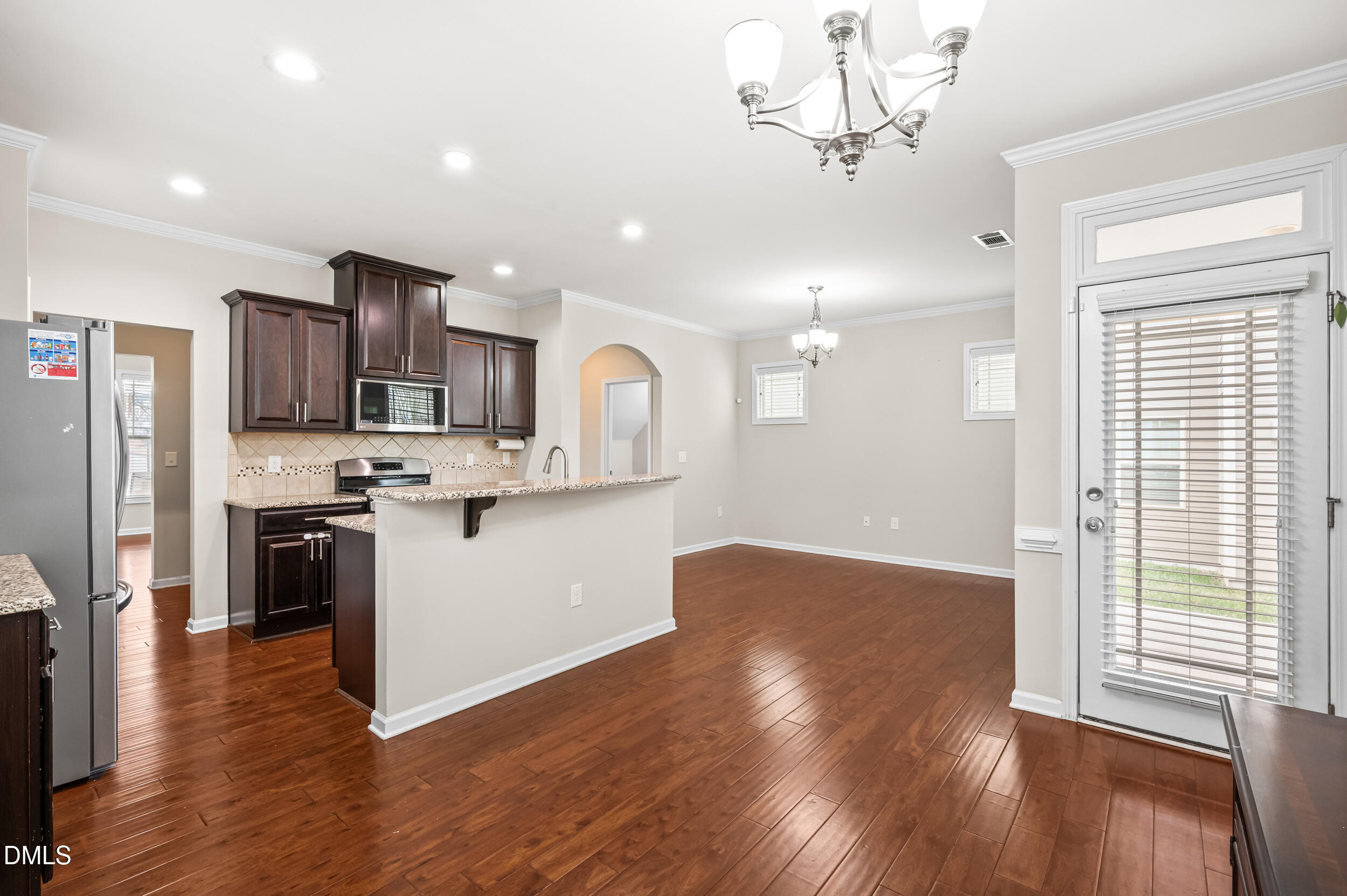1301 Oatney Ridge Lane Morrisville, NC 27560 - Photo 18 of 38 a kitchen with stainless steel appliances kitchen island granite countertop a refrigerator a sink dishwasher a stove and a dining table with wooden floor