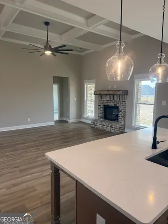 an empty room with wooden floor a fireplace a ceiling fan and windows