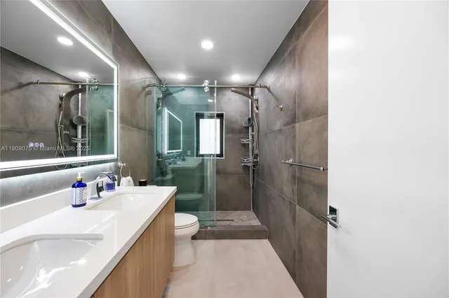a bathroom with a sink a toilet a shower and a mirror