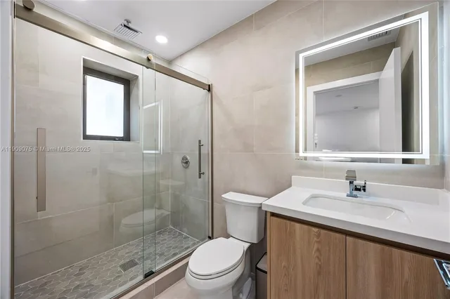 a bathroom with a toilet a sink a glass door a shower and a mirror