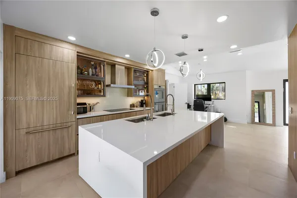 a large kitchen with stainless steel appliances a large counter top a stove and a refrigerator