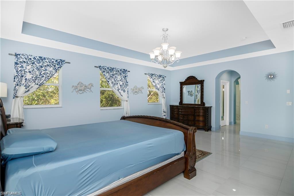 2181 Vardin Place Naples, FL 34120 - Photo 22 of 37 a bedroom with a bed mirror and window