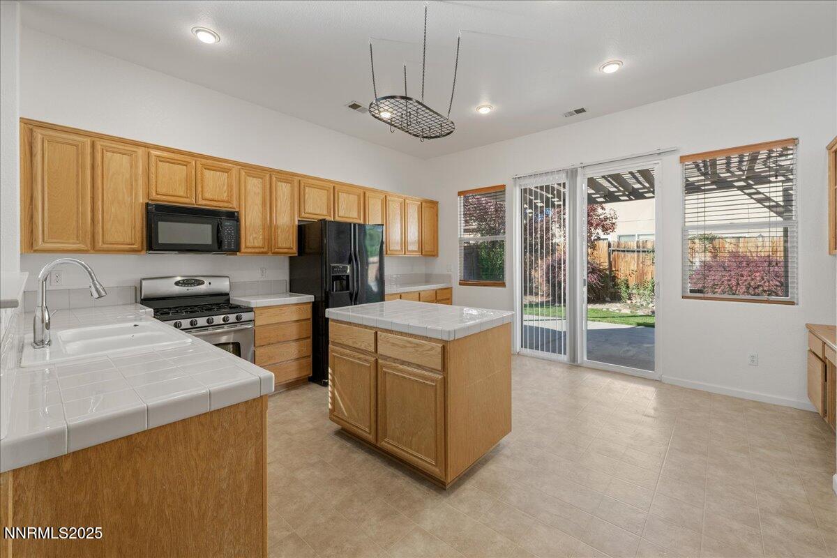 10583 Crystal Bay Drive Reno, NV 89521 - Photo 13 of 43 a kitchen with stainless steel appliances granite countertop a stove top oven a sink dishwasher a refrigerator and a dining table with large window