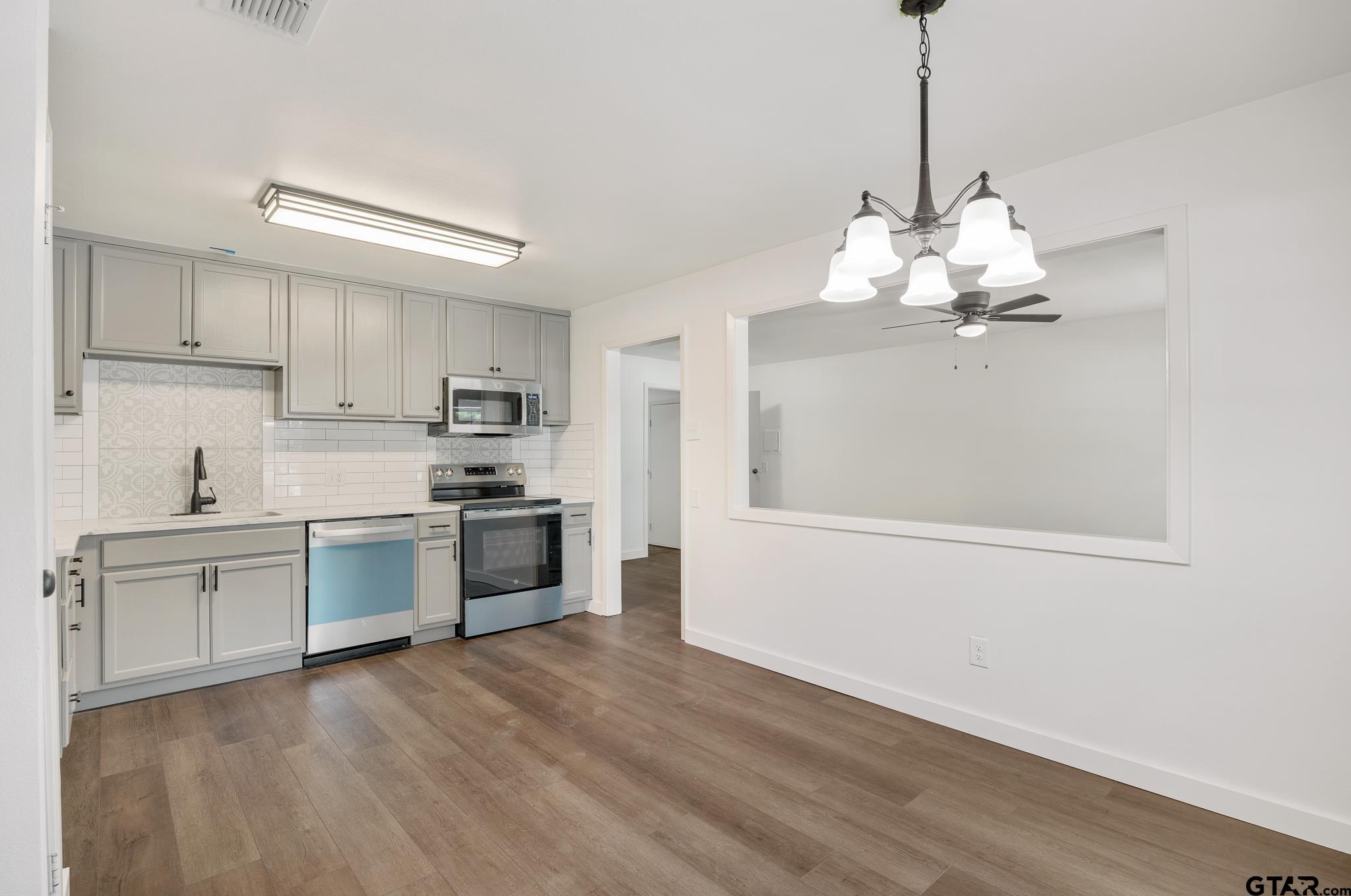 1538 North Hill Road Tyler, TX 75702 - Photo 8 of 29 a kitchen with stainless steel appliances granite countertop a dishwasher a stove a refrigerator and white cabinets with wooden floor