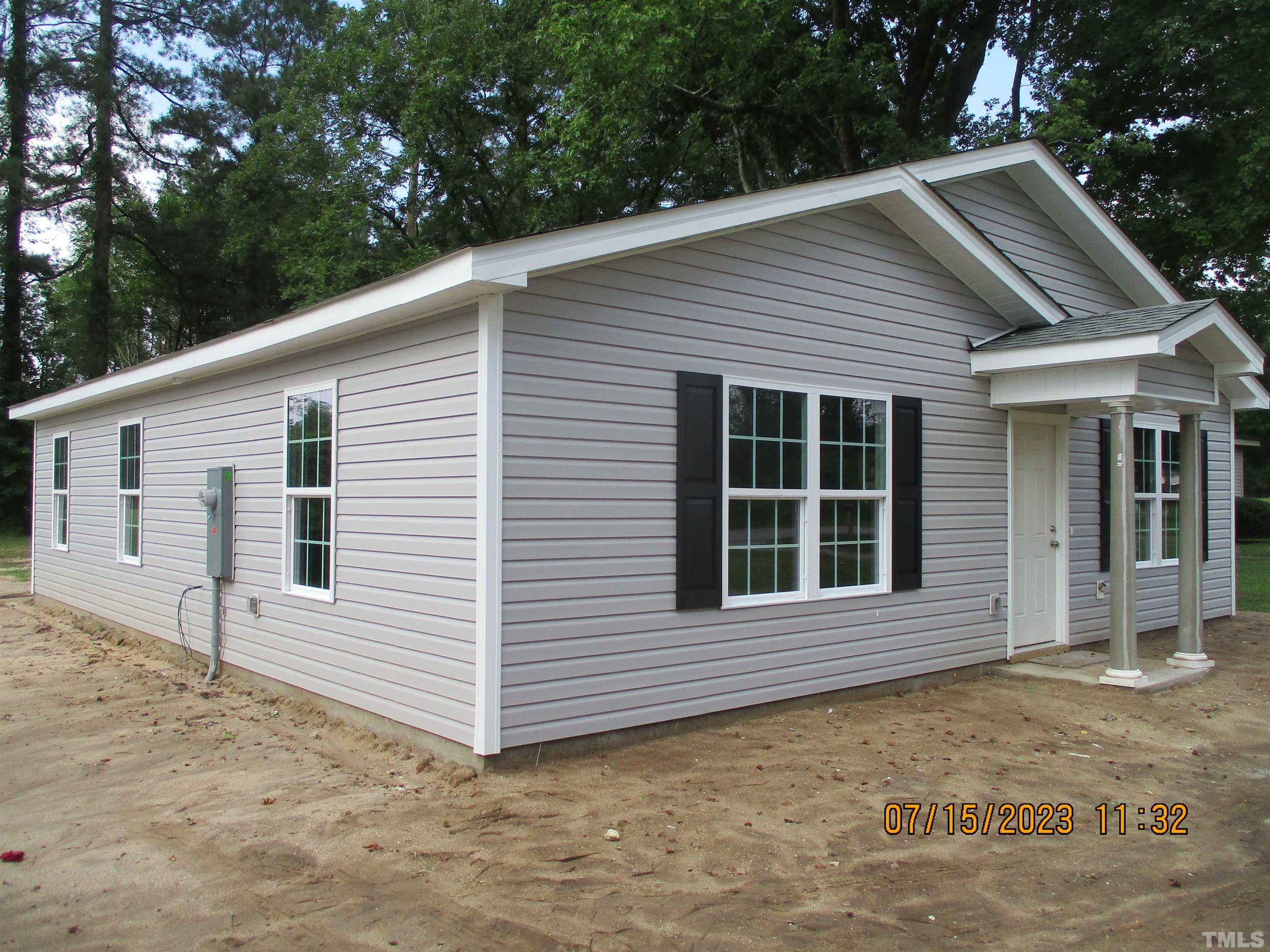 a view of house with backyard and trees in the background