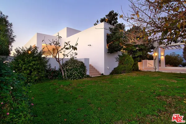 a front view of a house with a yard and potted plants