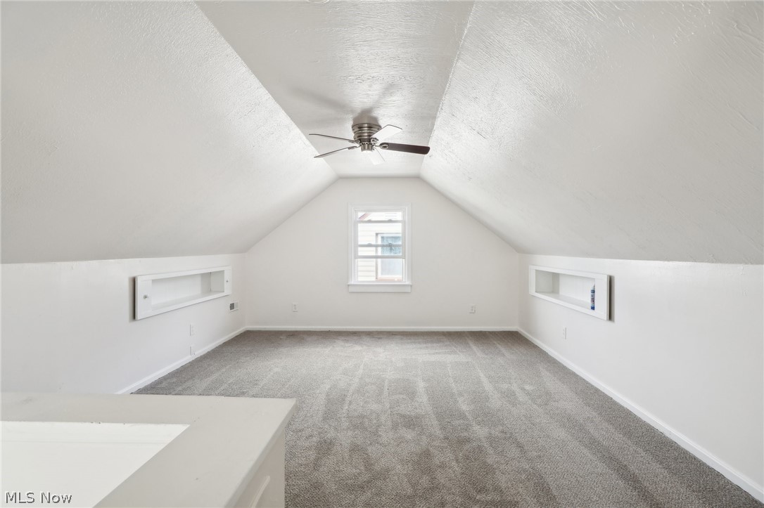 15901 Rockside Road Maple Heights, OH 44137 - Photo 2 of 2 Additional living space featuring ceiling fan, vaulted ceiling, built in features, a textured ceiling, and carpet